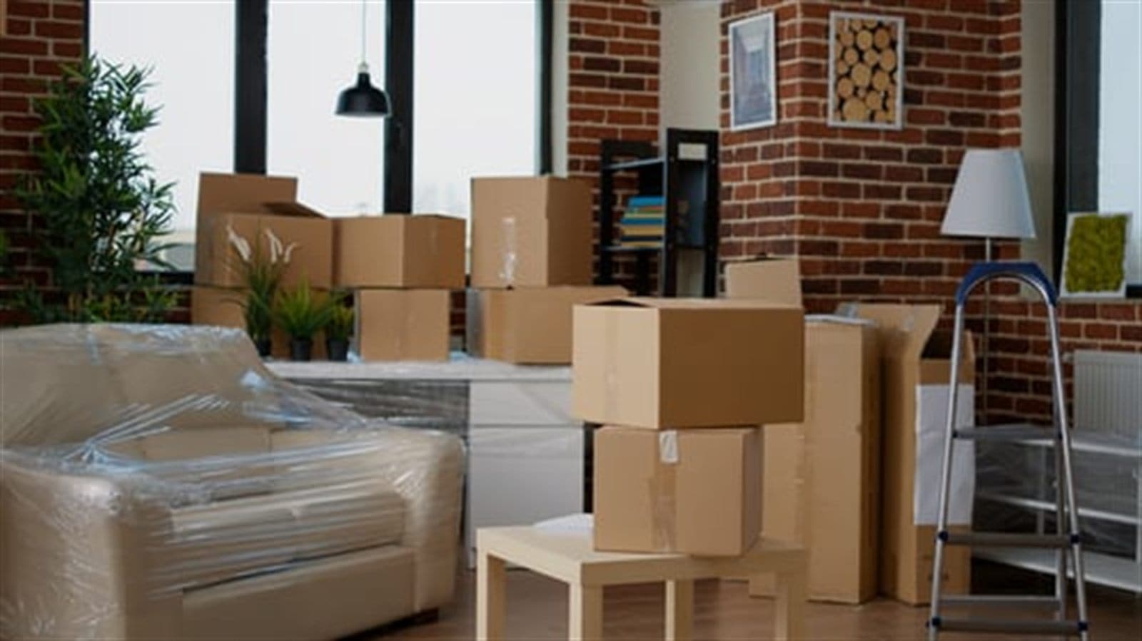 Furniture wrapped for protection beside packed boxes in a loft apartment ready for a professional move